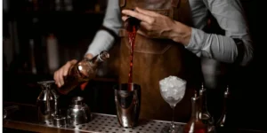 Barman preparando um drink no balcão de uma bebida de cor avermelhada