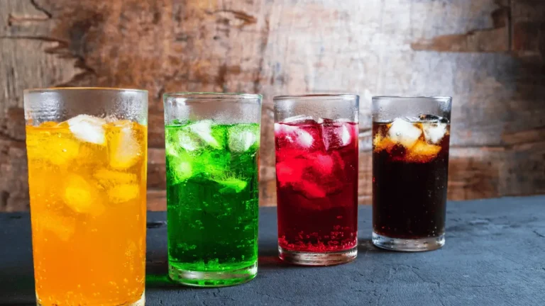 Imagem de quatro copos, um ao lado do outro, com diferentes soft drinks de cores difrentes também.