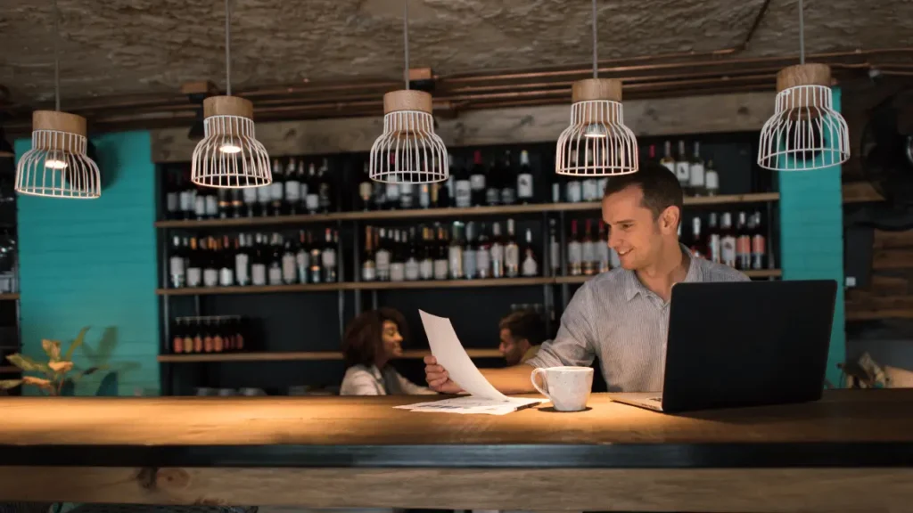 Homem atrás do balcão de bar analisando papéis