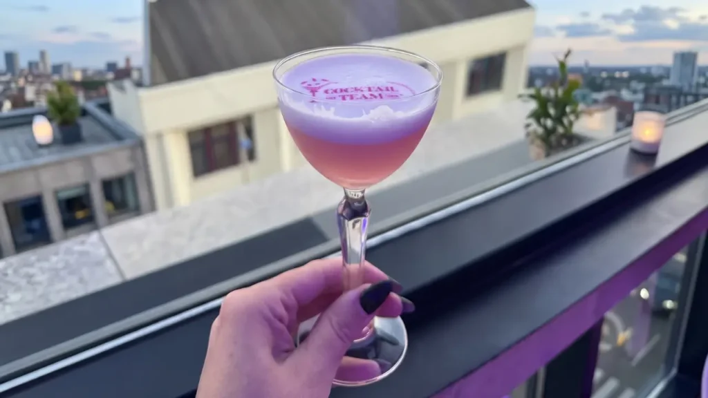 mão de uma mulher segurando um drink com nome de uma marca