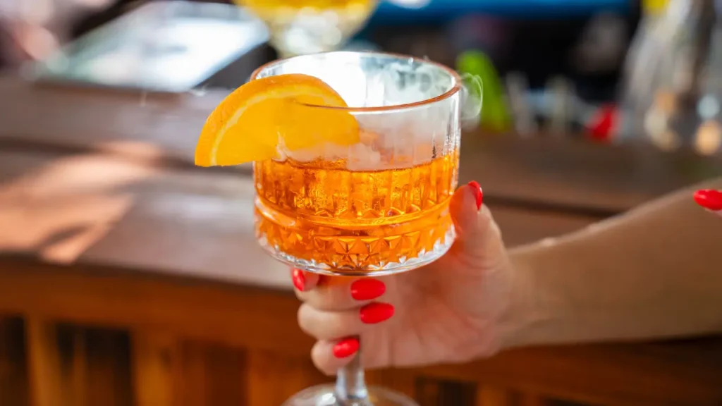 imagem de uma mão de mulher segurando um drink de cocktail